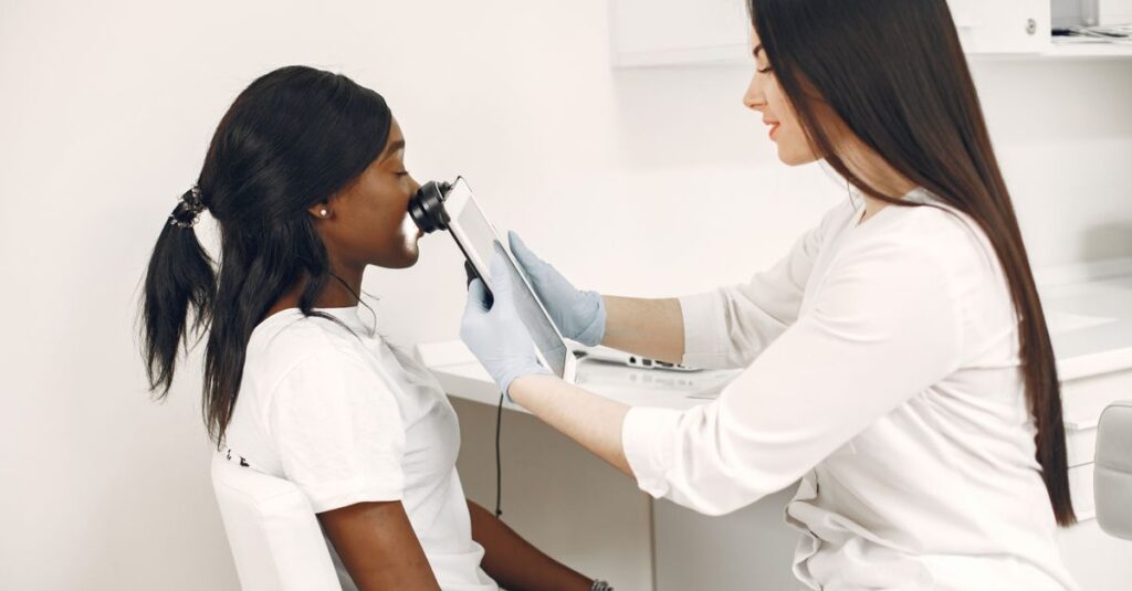 Profissional de saúde examinando rosto de paciente com aparelho.